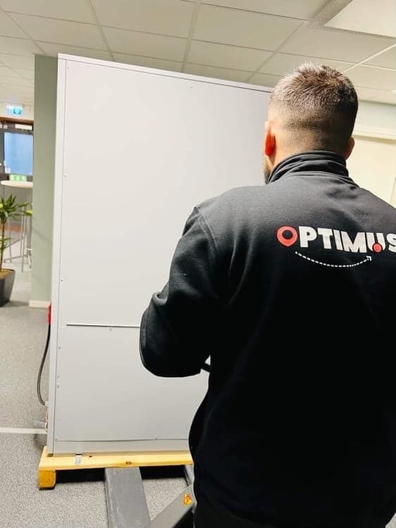 En flyttare från Optimus kör ett stort skåp på en pallyft genom ett kontor